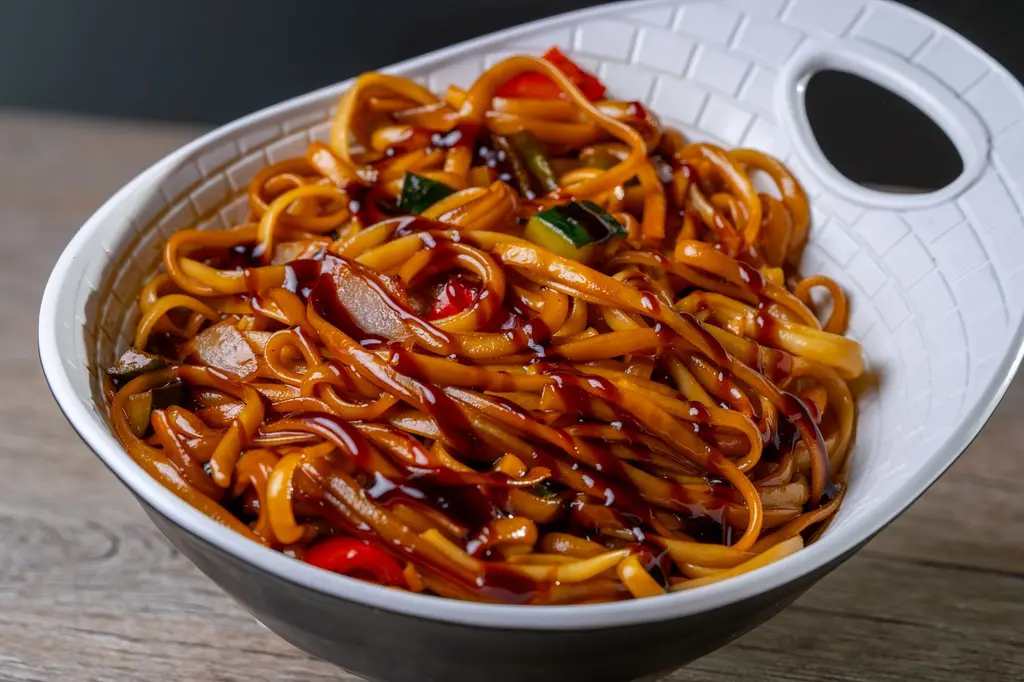 Scrumptious Asian-style noodles drizzled with a dark soy sauce glaze in a white bowl.