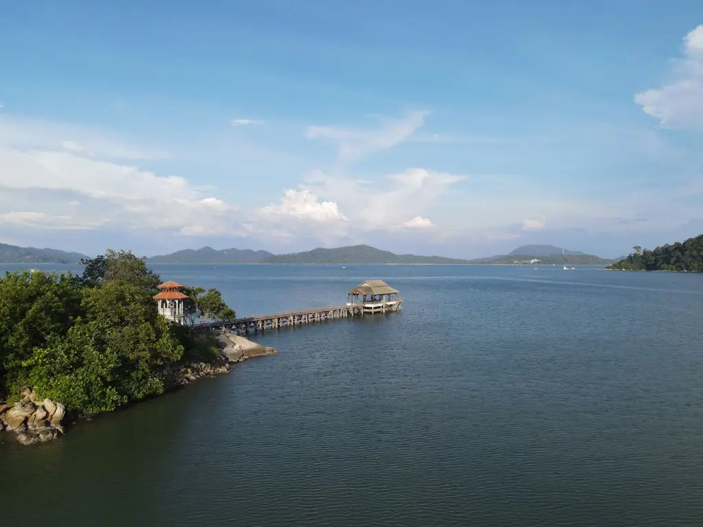 A serene view of a wooden pier extending into the sea at Pangkor Island, Malaysia.