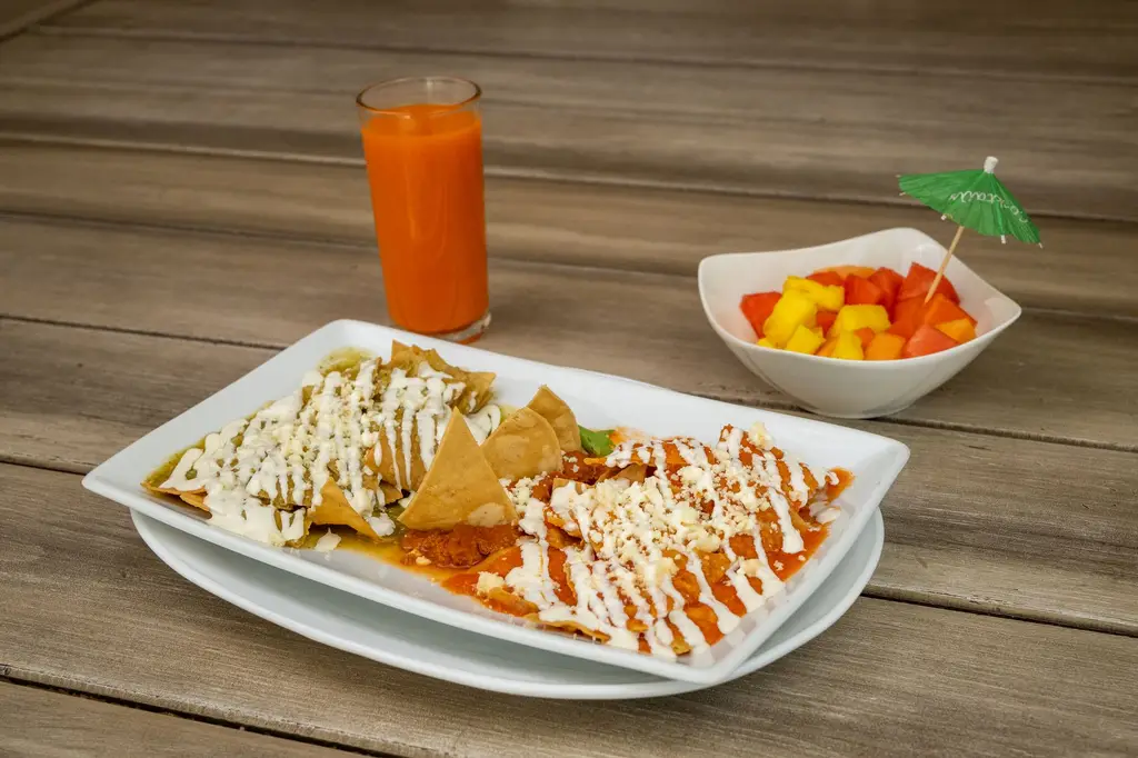 Appetizing Mexican breakfast with chilaquiles, juice, and tropical fruit bowl.