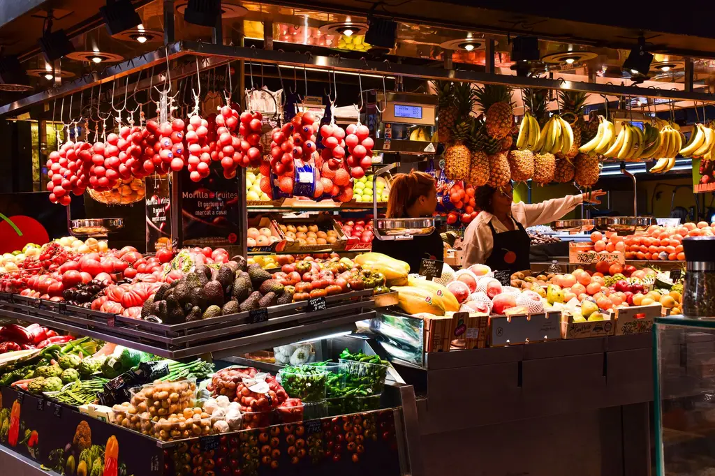 Colorful fruit stand in La Boqueria Market, Barcelona, showcasing fresh produce under warm lights.