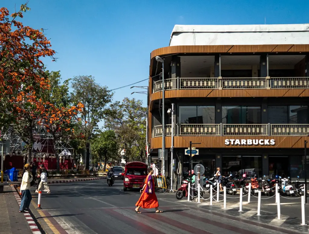 Bustling street in Chiang Mai with a Starbucks and pedestrians crossing in daylight.