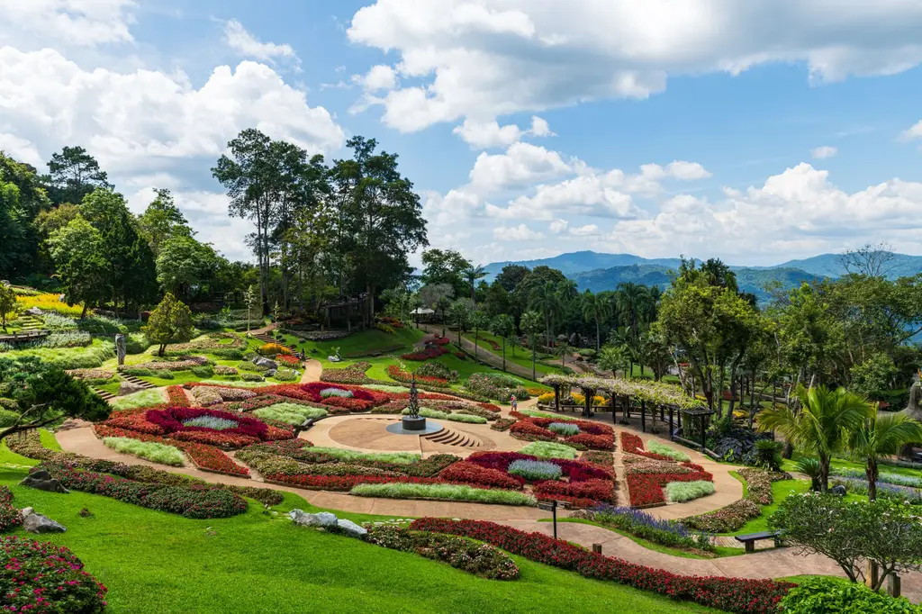 Stunning landscaped garden at Doi Tung Royal Villa, Chiang Rai, Thailand, surrounded by lush greenery and mountains.