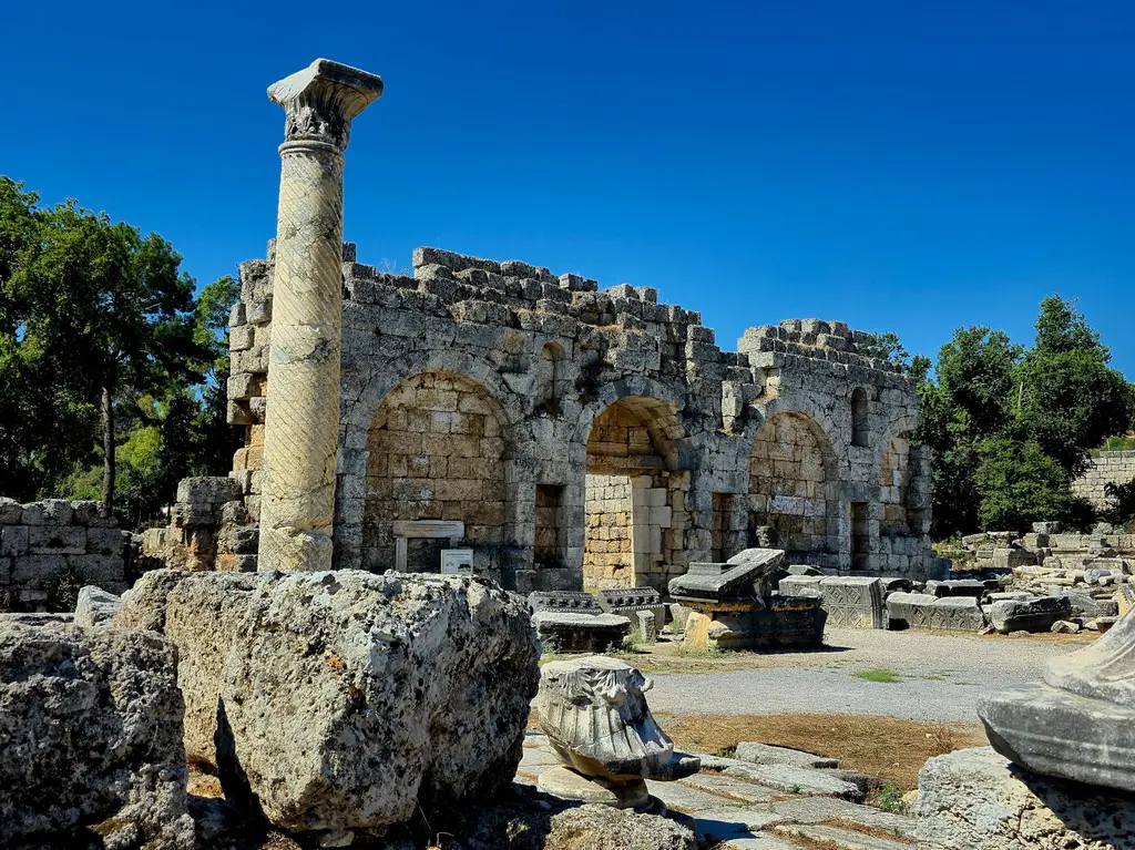 Explore the ancient stone ruins of Perge under a clear blue sky in Antalya, Turkey.