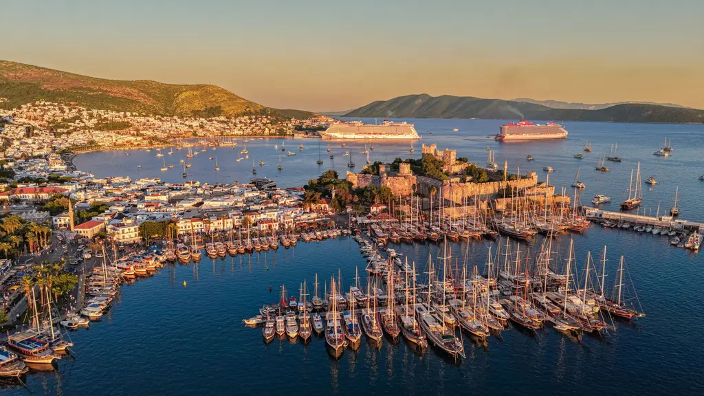 A stunning aerial photograph showcasing Bodrum's harbor, yachts, and ancient castle at sunset.