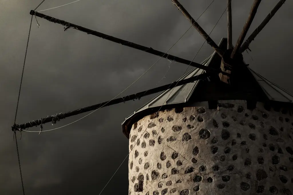 A rustic windmill stands tall against dark storm clouds in Bodrum, Turkey.