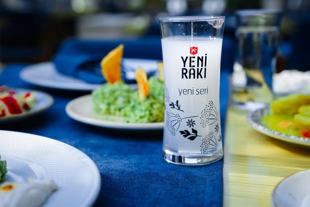 Yeni Raki glass on a vibrant Turkish dining table setting with assorted dishes.