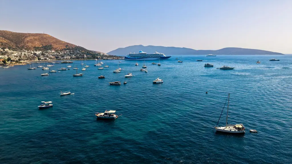 Vibrant Bodrum bay with sailing boats and cruise ship on a sunny day, capturing summer's essence.