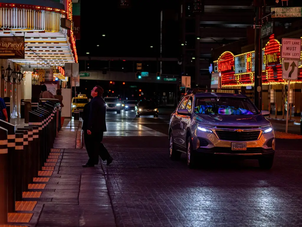 Vibrant night scene on Fremont Street, Las Vegas with cars and neon lights.