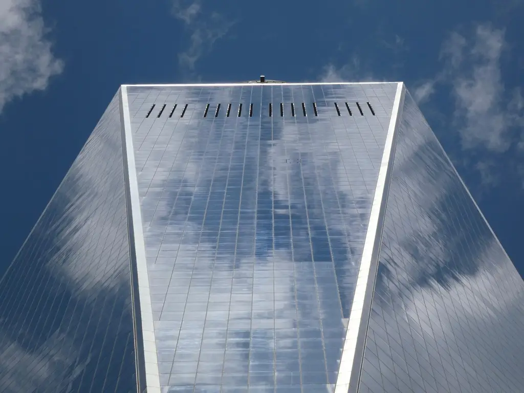 Low angle view of One World Trade Center reflecting clouds in New York City.