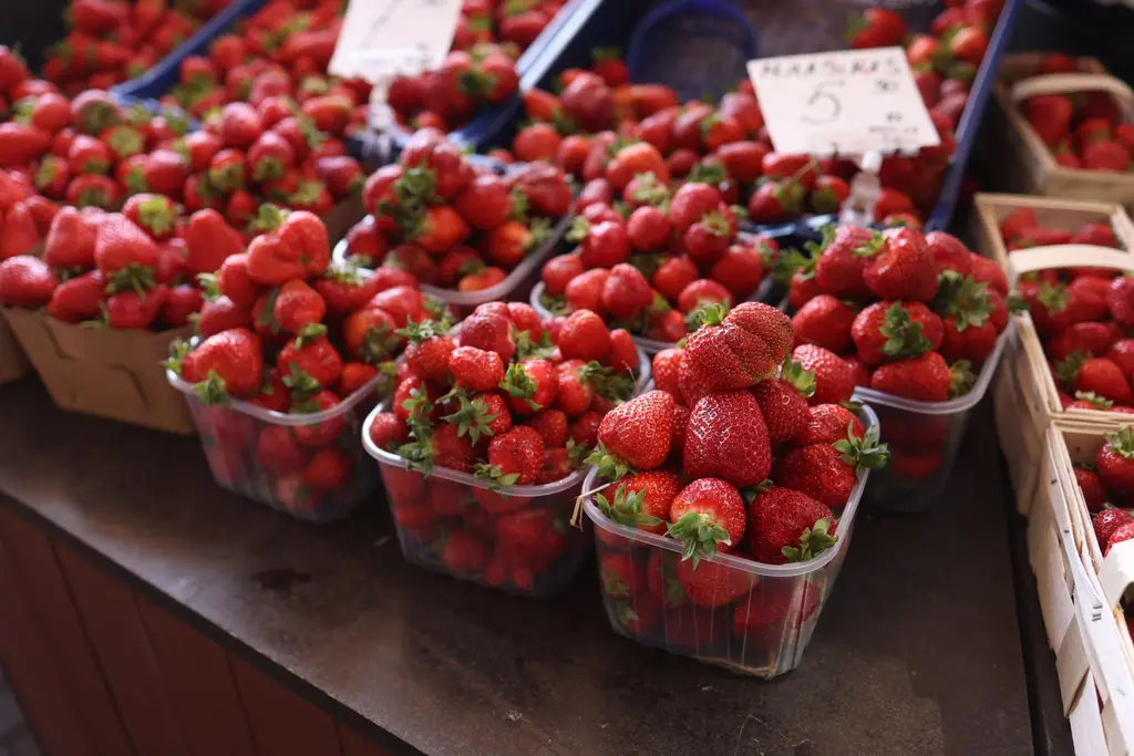 Vibrant red strawberries in baskets at an outdoor market, showcasing freshness and abundance.