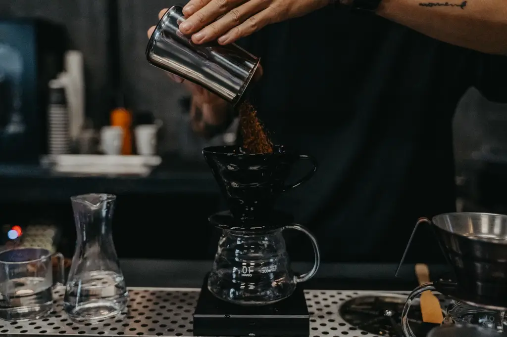Close-up of a barista making pour-over coffee in a cafe with precise technique.