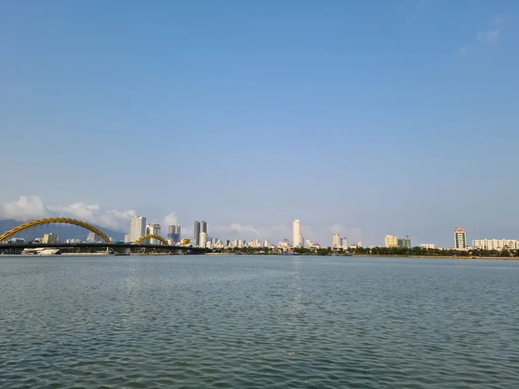 Beautiful view of Da Nang skyline with Dragon Bridge over River Han under clear blue sky.