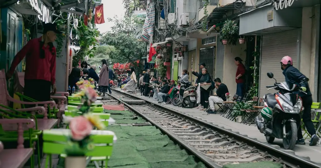 People sitting near train tracks in a busy street