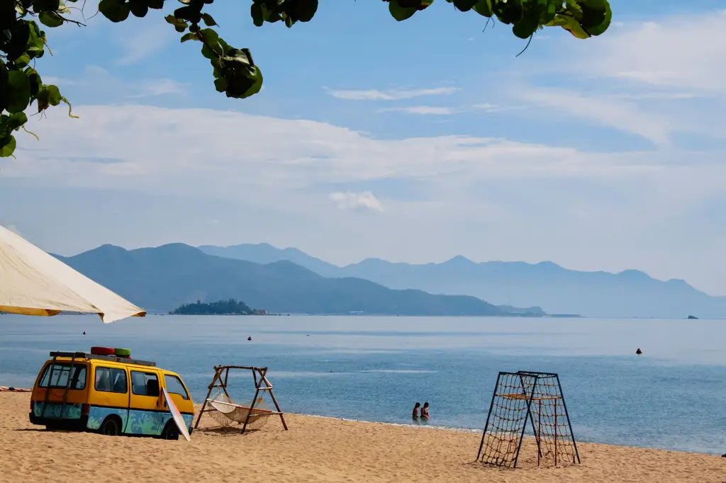 Idyllic beach scene in Nha Trang, Vietnam with parked bus and ocean view.