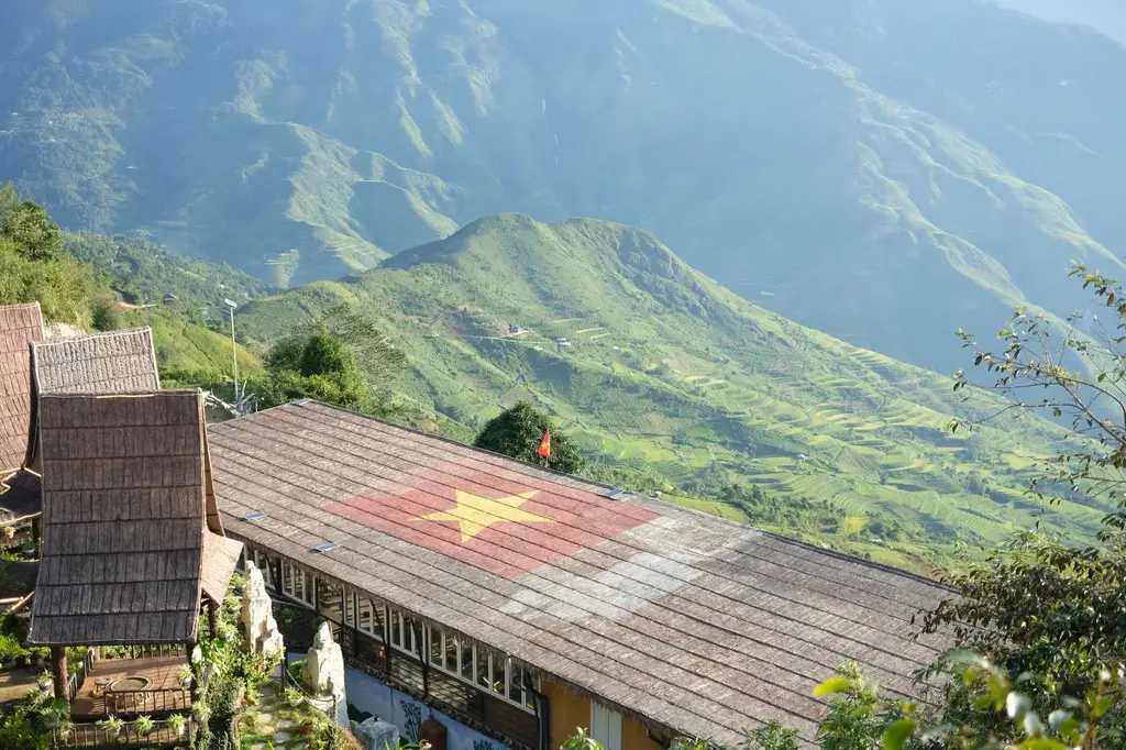 Scenic view of Vietnamese flag on rooftop with mountainous background in Sapa, Vietnam.
